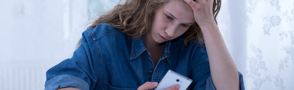 teen suffering from anxiety looking at phone and social media