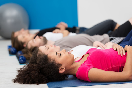 people lying down on their backs in yoga class breathing focused to combat anxiety in teens