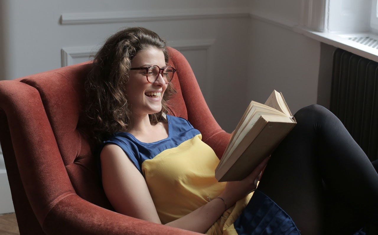 woman in chair laughing and reading 