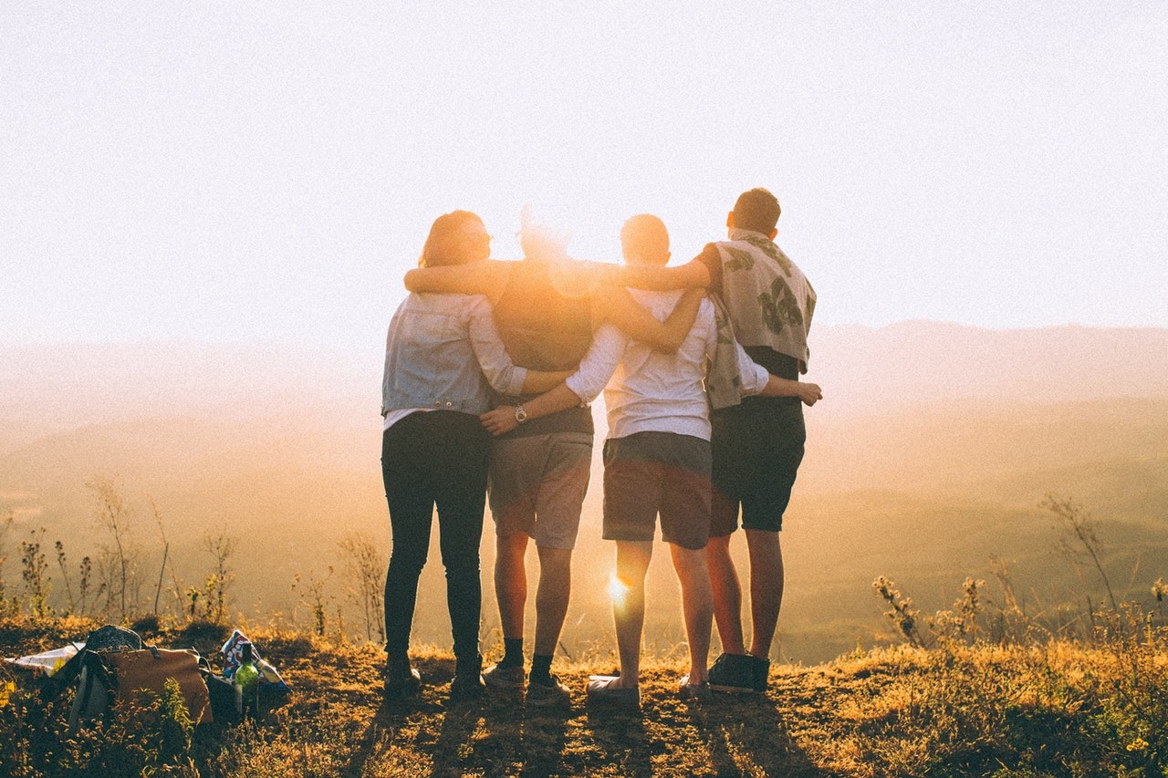 friends arms over each-other looking at sunset