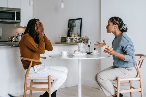 Multiethnic couple quarrelling at table in light apartment