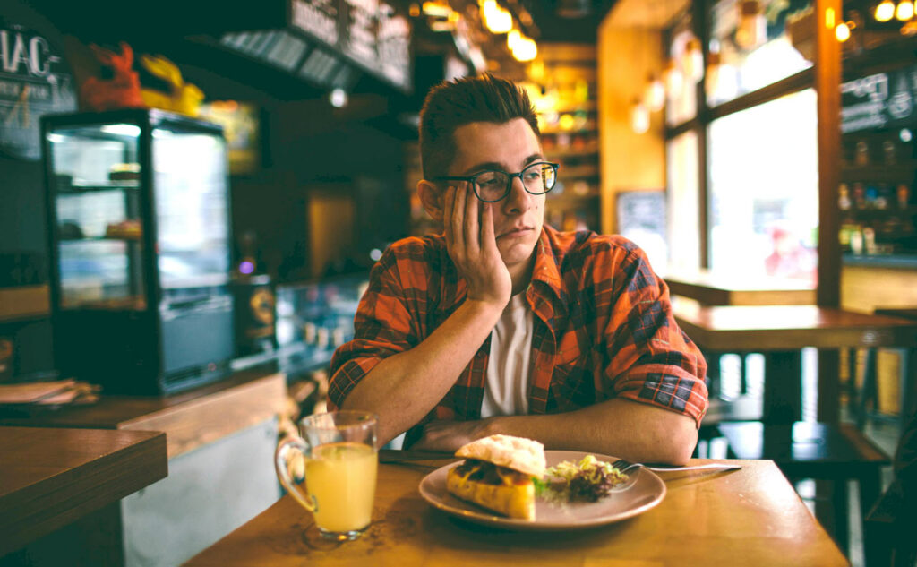 Eating Disorder Therapy -Man with no appetite sitting in restaurant