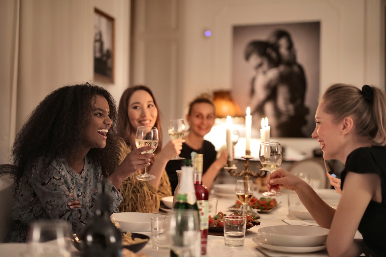 Support group of women having dinner in drinks while sharing strategies for coping with a narcissist.