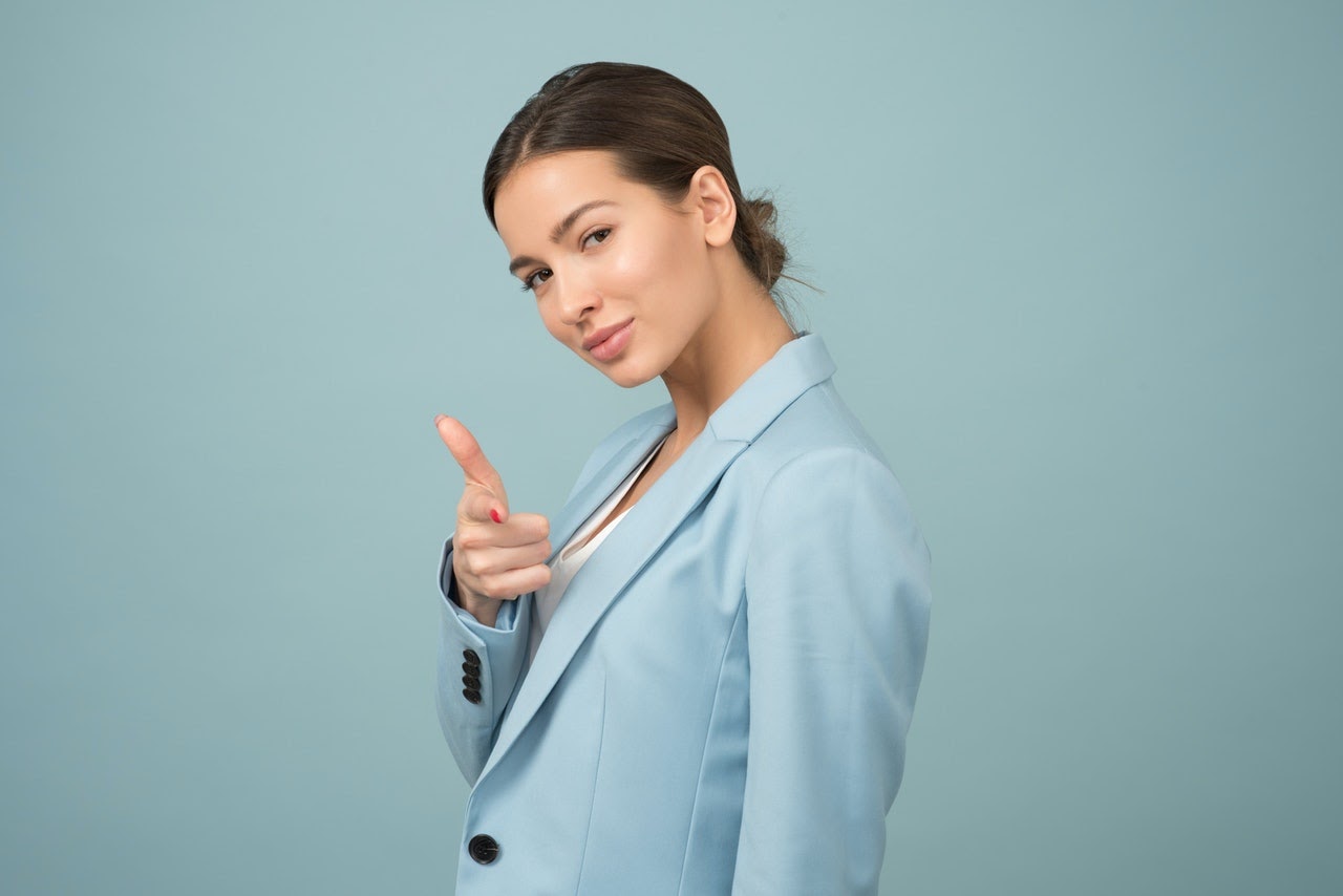 Woman smirking and pointing directly in front of her.