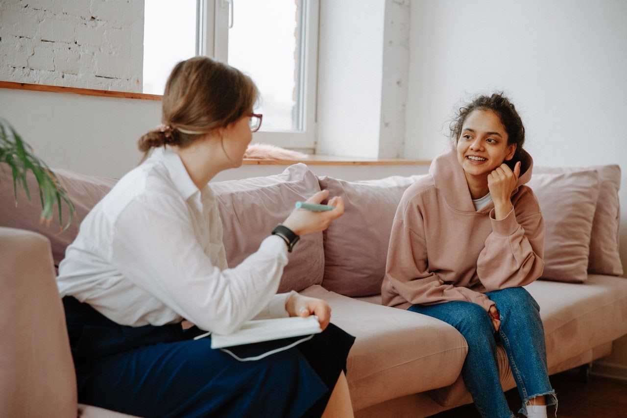 Therapist having a conversation with a patient who is involved with a narcissist on a couch.