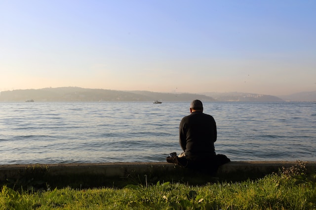 man sitting alone looking out at water