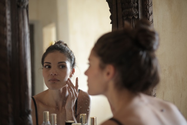 photo of a women looking at herself in the mirror